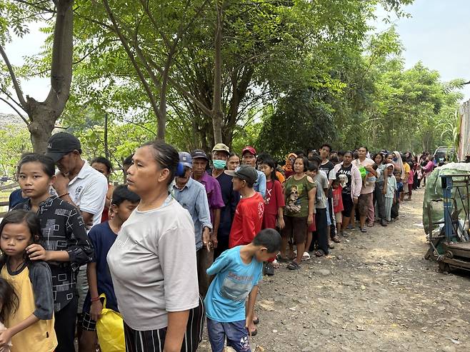 인도네시아 탕에랑 세완마을 주민들이 17일(현지시간) 마을 입구에서 도시락을 받기 위해 긴 줄을 서고 있다.