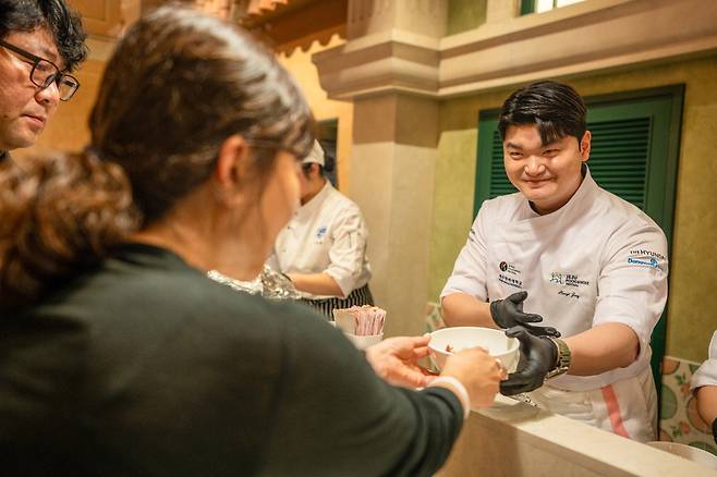 지난 16일 제주도 '제주신화월드'에서 열린 '제주푸드앤와인페스티벌'의 한 코너인 '고메디너'에서 장한이 요리사가 방문객에게 음식을 건네주고 있다. 코리아푸드앤와인페스티벌