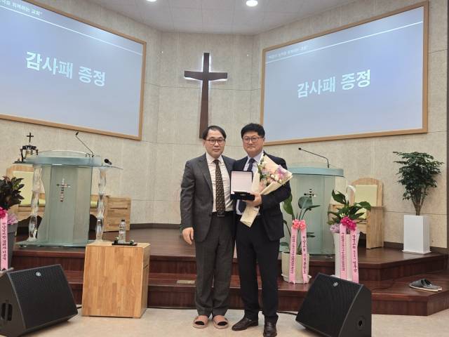 김태중 담임목사가 김종심 권사에게 감사패를 수영하고 기념 촬영을 갖고 있다. 단양=이상복 기자