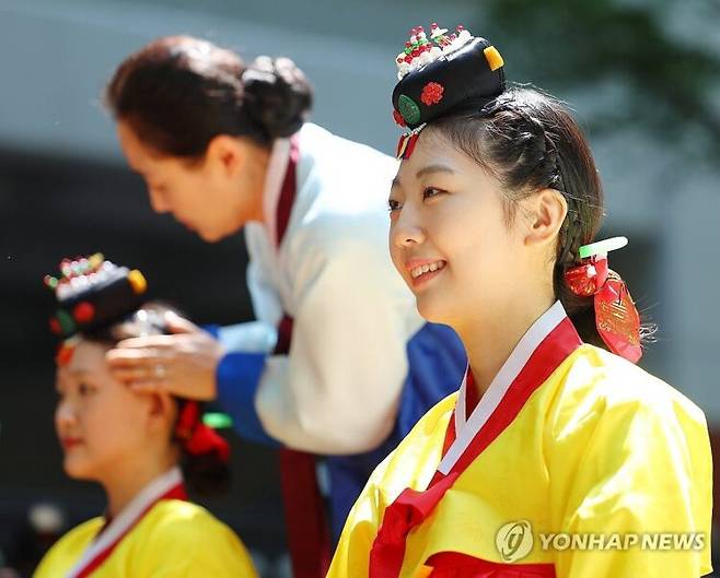 18일 서울 중구 덕수궁 돌담길에서 열린 전통 성년례 재현 행사에서 올해 성년이 된 참가자가 성년이 된 표시로 족두리나 갓을 쓰는 가관례(加冠禮)를 하고 있다. [사진=연합뉴스]