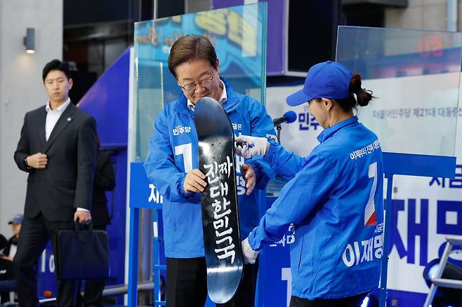 이재명 더불어민주당 대통령 후보가 19일 오후 서울 마포구 홍대 레드로드를 찾아 유세에 앞서 '진짜 대한민국'이라고 적힌 스케이트 보드를 선물받고 있다./뉴스1
