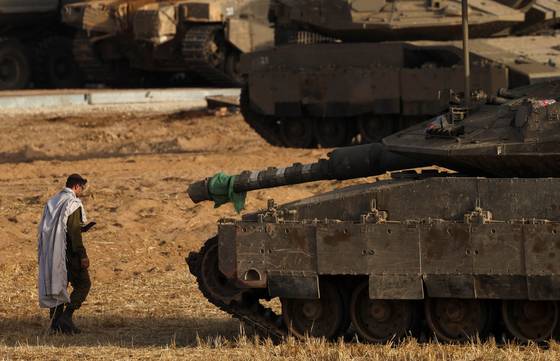 19일(현지시간) 이스라엘과 가자지구 접경에서 한 이스라엘 군인이 탱크 옆에서 아침 기도를 하고 있다. 로이터=연합뉴스