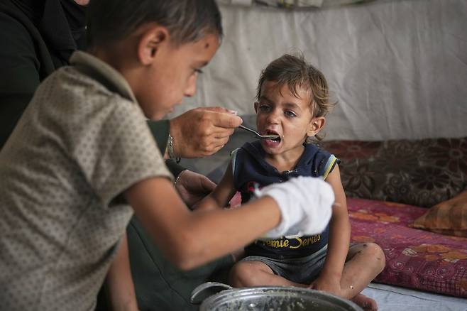 18일(현지시간) 가자지구 남부 칸유니스의 한 난민 캠프에서 팔레스타인 소년이 음식을 먹고 있다. 로이터연합뉴스