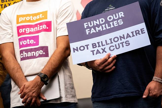 미국 시민단체 관계자들이 지난 13일(현지시간) 워싱턴에서 메디케이드·푸드 스탬프 예산 삭감 반대 기자회견을 열고 “억만장자 세금을 깎아주지 말고, 우리 가족을 지원해달라”라고 적힌 팻말을 들고 있다. 로이터·연합뉴스