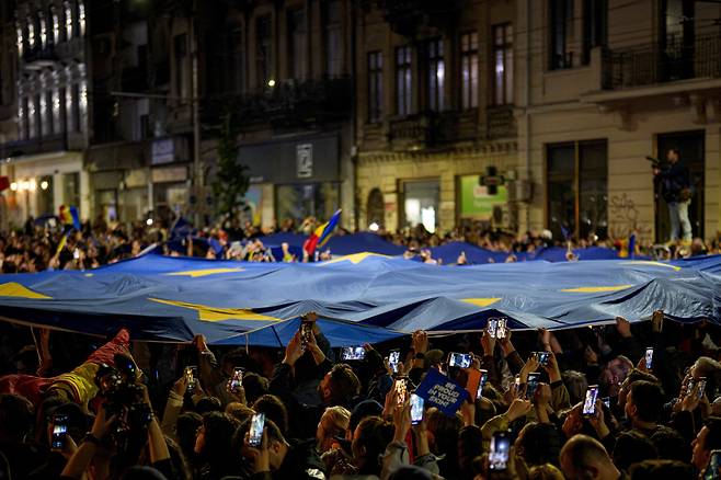 승리의 상징 된 EU 깃발 루마니아 대통령 선거가 치러진 18일(현지시간) 부쿠레슈티에서 니쿠쇼르 단 후보 지지자들이 대형 유럽연합(EU) 깃발을 들고 있다. AP연합뉴스