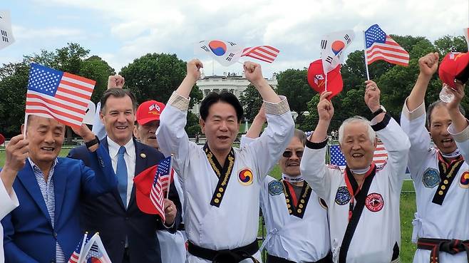 미국 백악관 앞서 열린 태권도 축제 (워싱턴=연합뉴스) 김동현 특파원 = 이동섭 국기원장(가운데)이 18일(현지시간) 워싱턴DC 백악관 인근 공원에서 열린 국기원 주최 한마음 태권도 축제에서 태극기와 성조기를 들고 있다. 이 원장 왼쪽에 톰 수오지 하원의원(민주·뉴욕)이 있다. 2025.5.18