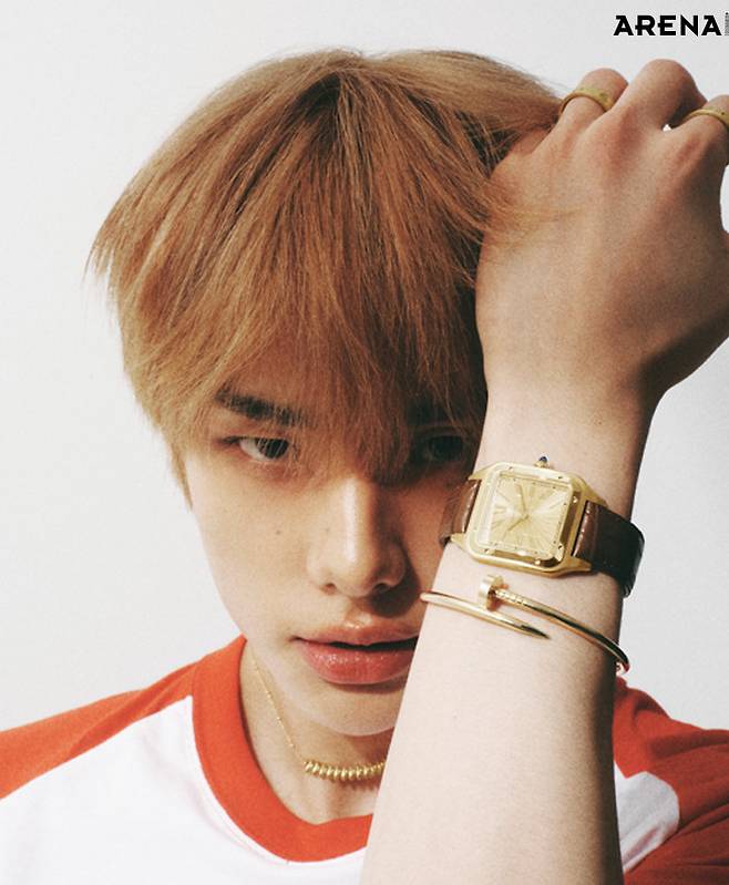 왼손에 착용한 옐로 골드 케이스와 골드 브라운 앨리게이트 가죽 스트랩의 산토스 뒤몽 워치 엑스트라 라지·옐로 골드 소재의 저스트 앵 끌루 브레이슬릿 클래식·검지와 약지의 옐로 골드 LOVE 링 클래식·옐로 골드 소재의 클래쉬 드 까르띠에 네크리스 스몰 모두 까르띠에 제품. 티셔츠 스타일리스트 소장품.