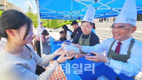 20일 정오 목원대 중앙도서관 앞에서 열린 ‘총장이 쏜다’ 행사에서 이희학 총장(오른쪽)이 한 학생에게 런치박스를 전달하고 있다. (사진=목원대 제공)