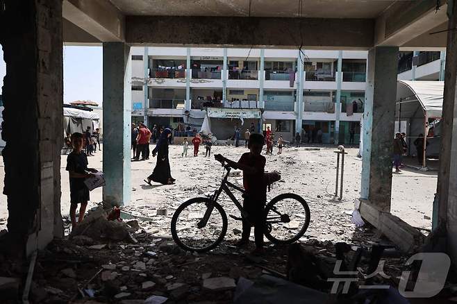 팔레스타인 소년이 19일(현지시간) 이스라엘의 중부 가자지구 난민 캠프 누세이라트 공습으로 폐허가 된 학교 앞에 서 있다 ⓒ AFP=뉴스1