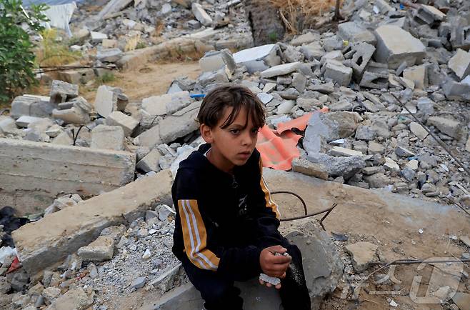 19일(현지시간) 팔레스타인 가자지구 남부 칸유니스에서 이스라엘의 공격 이후 한 팔레스타인 소년이 건물 잔해 위에 앉아 있다. 2025.05.19 ⓒ 로이터=뉴스1 ⓒ News1 최종일 선임기자