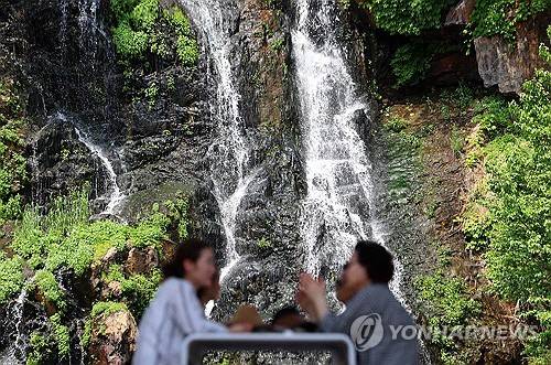 전국 대부분 낮 기온이 25도 이상을 기록하는 등 초여름 날씨를 보인 20일 서울 서대문구 홍제폭포 산책로에서 설치된 대형 거울에 폭포 모습이 비치고 있다. [연합뉴스]