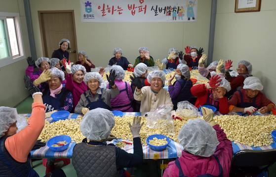 육거리시장 일하는 밥퍼 참여자들이 대형 테이블에서 마늘을 손질하고 있다. 김성태 객원기자