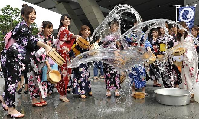 2010년 8월 일본 도쿄에서 기모노를 입은 여성들이 무더위를 경고하는 캠페인 중 물을 바닥에 뿌리고 있다./AFPBBNews=뉴스1