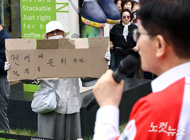 김문수 국민의힘 대선 후보가 16일 오후 충남 천안 신세계백화점 천안아산점 앞 광장에서 유세를 펼치며 지지를 호소하고 있는 가운데 한 시민이 '권영세, 권성동 은퇴하라'라고 적은 종이박스를 들어보이고 있다. 윤창원 기자