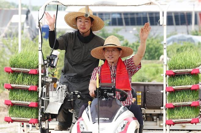 김문수 국민의힘 대통령 후보가 21일 경기 고양시 한 논에서 청년 농업인과 이앙기를 타고 손을 흔들고 있다.  뉴스1