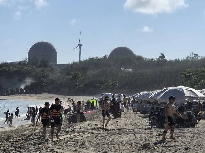 대만 최남단 핑둥현의 마안산 원전 2호기가 공식 폐쇄된 18일 대만 시민들이 원전 인근 해변에서 해수욕을 즐기고 있다. 원전 뒤로 원전을 대체해 전력을 공급할 풍력발전기가 보인다. 장영식 사진작가 제공