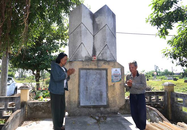 베트남 꽝남성 반꾸엇 학살 생존자 응우옌티씨와 쯔엉떤트엉이 2025년 4월28일 당시 숨진 가족들의 이름이 새겨진 위령비 앞에서 두 손을 모아 추모하고 있다.