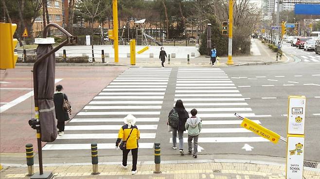 ​경기 화성시 동화초교 앞 스쿨존에서 어린이들이 횡단보도를 건너고 있다. 이곳에는 무단횡단을 감지해 신호를 제어하고 자동으로 안전 바를 내려주는 인공지능(AI) 보행안전 시스템이 설치돼 있다.  화성시 제공