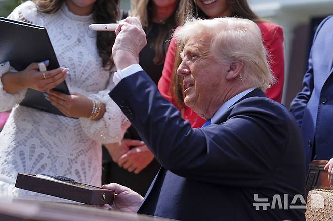 [워싱턴=AP/뉴시스] 도널드 트럼프 미국 대통령이 19일(현지 시간) 백악관 로즈가든에서 멜라니아 여사와 함께 복수 포르노 금지법인 '테이크 잇 다운' 법안(Take it Down Act)에 서명한 후 펜을 들어 보이고 있다. 이 법안은 인공지능(AI) 기반의 '딥페이크' 이미지까지 포함해 온라인에서의 사생활 침해에 강력히 대응하는 내용을 담고 있다. 2025.05.20.