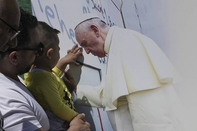 지난 4월 25일 요르단 서안지구 베들레헴에 있는 이스라엘의 분리 장벽 근처에서 한 소년이 현수막에 인쇄된 프란치스코 교황의 사진을 만지고 있다. [사진 | 뉴시스]