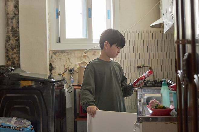재영 군(대역)이 낡은 부엌에서 라면을 꺼내고 있다. 굿네이버스 제공.