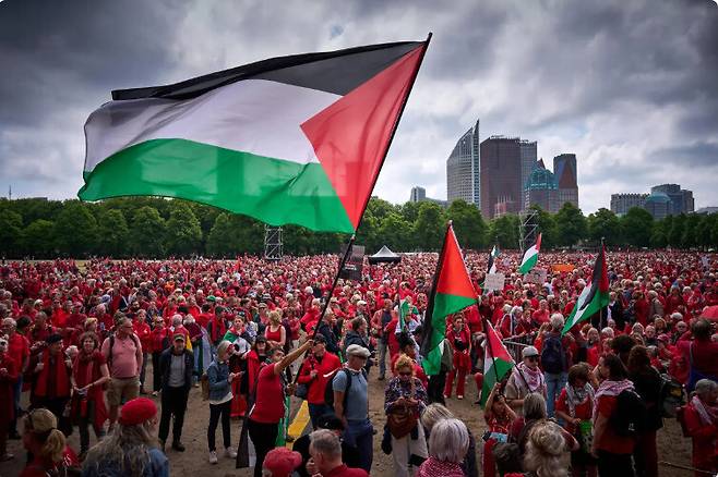 네덜란드 헤이그에서 지난 18일 수만 명의 시민들이 팔레스타인 주민에 대한 지지의 표시로 빨간 상의를 입고는 가자에서 이스라엘의 학살을 중단하는데 네덜란드 정부가 나서라는 시위를 벌이고 있다. 이날 시위는 네덜란드에서 벌어진 지난 20년 만의 최대 규모이다. 알자지라 방송 누리집 갈무리