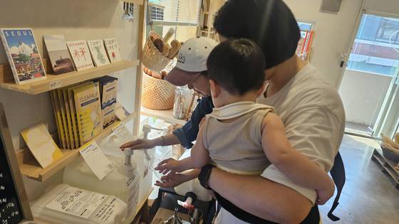 21일 오후 4시 서울 성동구 송정동 소재 제로웨이스트 상점 '베러얼스'에서 이슬기(35)씨가 아들 오한결(1)군과 함께 유아용 세제를 구입하고 있다. 문혜민 베러얼스 대표가 아기를 안은 손님을 위해 세제를 대신 담고 있다. 사진 정은혜 기자