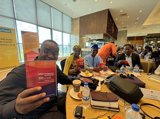 AEA총회 참석자가 케냐 나이로비 올레 세레니 호텔에서 열린 총회에서 '서울총회를 위한 100대 기도제목'을 들어보이고 있다. AEA 제공