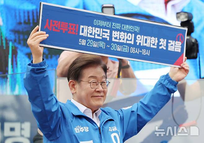 [양산=뉴시스] 조성우 기자 = 이재명 더불어민주당 대선후보가 22일 경남 양산시 양산워터파크공원에서 열린 집중유세에서 사전투표 독려 현수막을 전달 받은 뒤 들어보이고 있다. (공동취재) 2025.05.22. photo@newsis.com