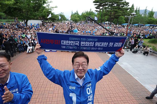 이재명 더불어민주당 대선후보가 22일 경남 양산시 양산워터파크공원에서 열린 집중유세에서 사전투표 독려 현수막을 전달 받은 뒤 들어보이고 있다./뉴시스