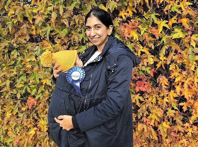 수엘라 브레이버만 영국 하원 의원은 검찰총장 재직 중이던 2021년 영국 내각 최초로 출산휴가를 다녀와 화제를 모았다. 이를 위해 영국은 당시 의회 주도로 법률을 개정해 장관급도 출산휴가를 갈 수 있도록 했다. 이후 그는 복직해 검찰총장을 지내다 내무부 장관에도 올랐다. 사진은 그가 임신부용 상의를 입고 아이를 품은 모습. /브레이버만 X(옛 트위터)