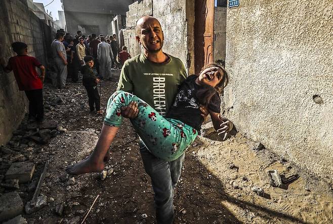 21일(현지시각) 가자 지구 북부 자발리아 난민 캠프에서 이스라엘의 공습 이후, 한 남자가 부상한 소녀를 안고 도움을 요청하고 있다. 가자 지구 민방위 대변인은 신화통신에 이스라엘군이 새벽부터 가자 지구에 수십 차례의 공습을 가해 이 지역 전역에서 최소 56명의 팔레스타인이 사망했다고 말했다. 자발리아/신화 연합뉴스