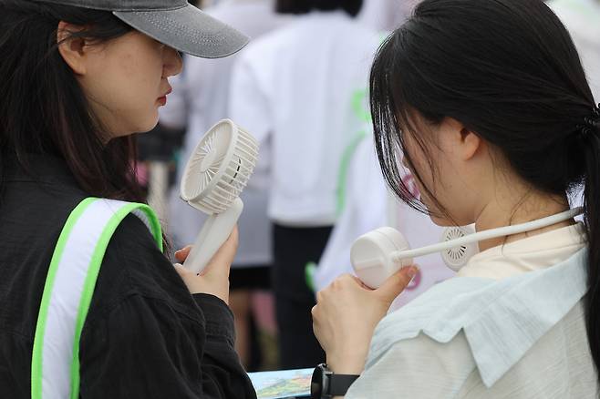 Visitors cool off with portable fans at the 2025 Olive Young Festa held at Nodeul Island in Yongsan, Seoul, Thursday, as hot weather continues. (Yonhap)