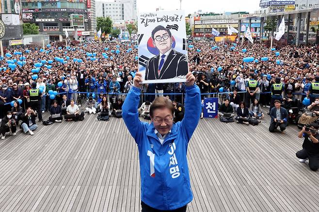 이재명 더불어민주당 대통령 후보가 24일 오후 경기도 부천시 부천역 북부광장에서 열린 유세에서 자신의 캐리커처 그림을 들어 보이고 있다. /뉴스1