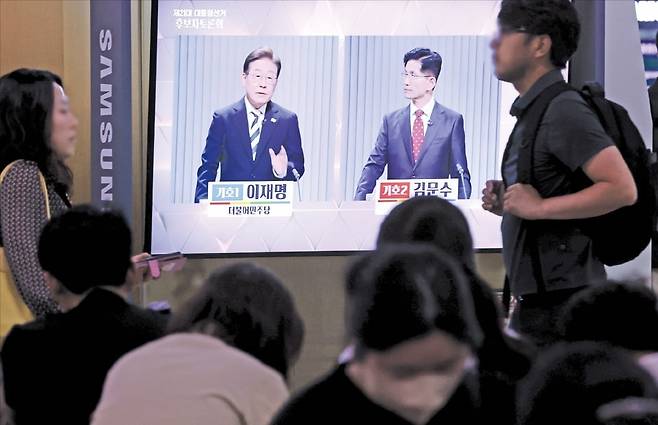 ‘6·3 대통령 선거’ 후보자 2차 TV 토론회가 열린 23일 서울역 대합실에서 시민들이 이재명 더불어민주당 후보(왼쪽)와 김문수 국민의힘 후보가 토론하는 모습을 보고 있다.  /연합뉴스