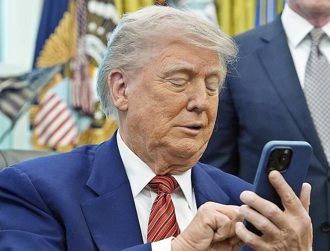 도널드 트럼프 미국 대통령이 23일(현지시간) 워싱턴 백악관에서 원자력 관련 행정명령에 서명한 뒤 휴대전화를 끄며 기자들과 대화하고 있다. AP연합뉴스