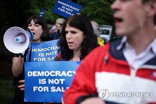 트럼프 밈코인 행사에 항의하는 시위대 (스털링<미 버지니아주> AFP=연합뉴스) 2025년 5월 22일 미국 버지니아주 스털링의 트럼프 내셔널 골프 클럽에서 열리는 비공개 만찬 행사에 항의하는 시위 참가자들이 골프 클럽 바깥에서 시위를 벌이고 있다. (Getty Images via AFP) 2025.5.24.