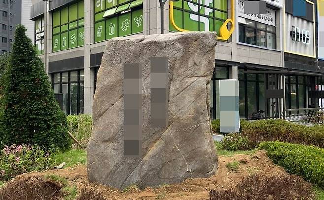 한 네티즌이 아파트 단지에 설치된 거대 조경석에 불만을 토로하며 첨부한 사진. 앞면에 아파트 이름이 서체로 큼지막하게 적혀 있다. /블라인드