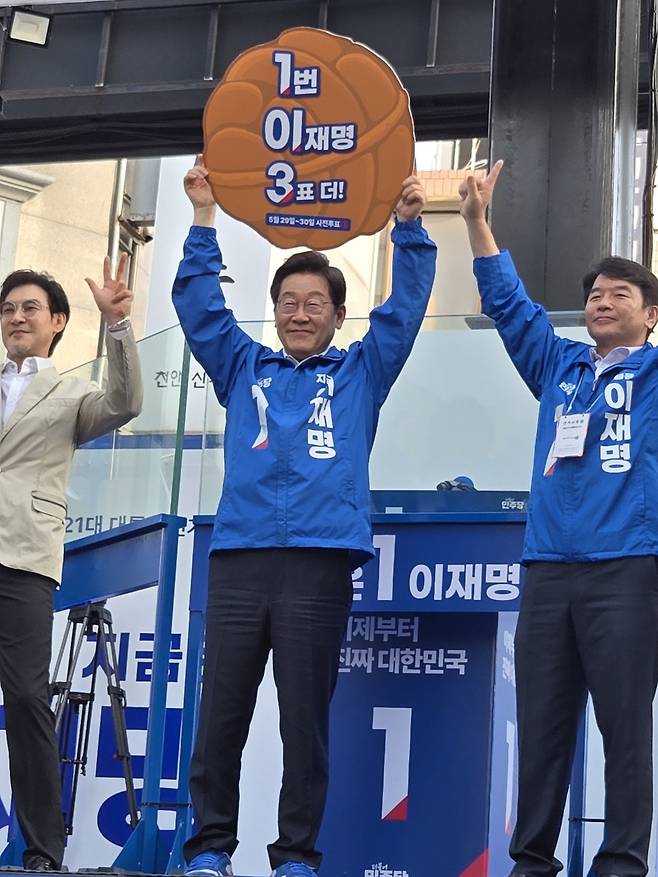 민주당 이재명 대선 후보가 25일 충남 천안시 신부문화거리를 찾아 문진석 충남도당 위원장으로부터 받은 '1번 이재명 3표 더!'라고 적힌 호두과자 모양 피켓을 들어올리고 있다. 박하늘 기자