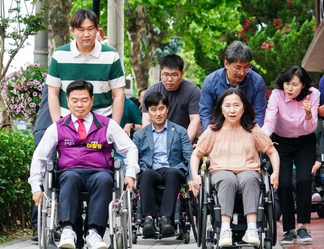 이필형(앞줄 왼쪽) 서울 동대문구청장이 지난 23일 지하철 장한평역 2번 출구부터 400m 구간을 휠체어로 이동하며 장애인들의 불편사항을 점검하고 있다. 동대문구청 제공