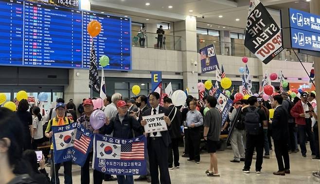 ▲인천공항 제1여객터미널 E환영홀에 몰려든 보수단체 회원들이 태극기와 성조기, 풍선, 피켓을 들고있다. /사진제공=독자