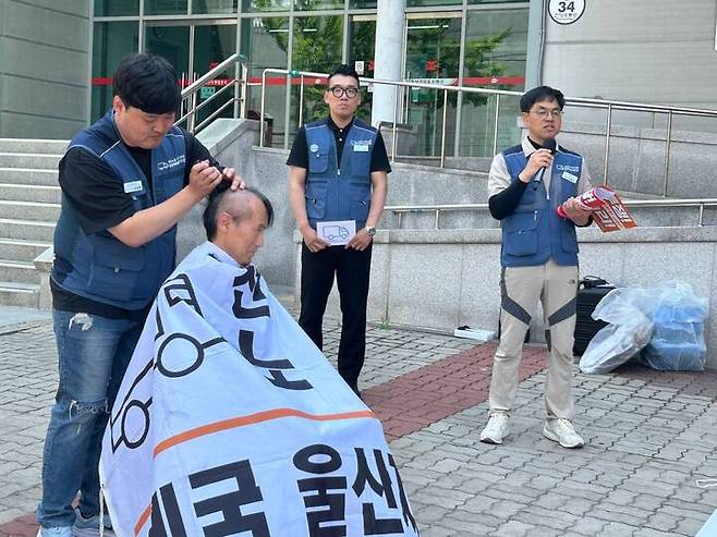 한 울산 우체국 택배 노동자가 26일 울산우편집중국 앞에서 열린 결의대회에서 단체협약 투쟁을 각오하며 머리를 밀고 있다. 택배노조 제공