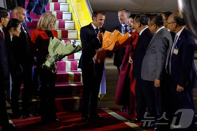 에마뉘엘 마크롱 프랑스 대통령(가운데)과 부인 브리지트 마크롱이 5월 25일 하노이 노이바이 국제공항에 도착해 베트남 관리들의 환영을 받고 있다. 2025.5.25 ⓒ AFP=뉴스1 ⓒ