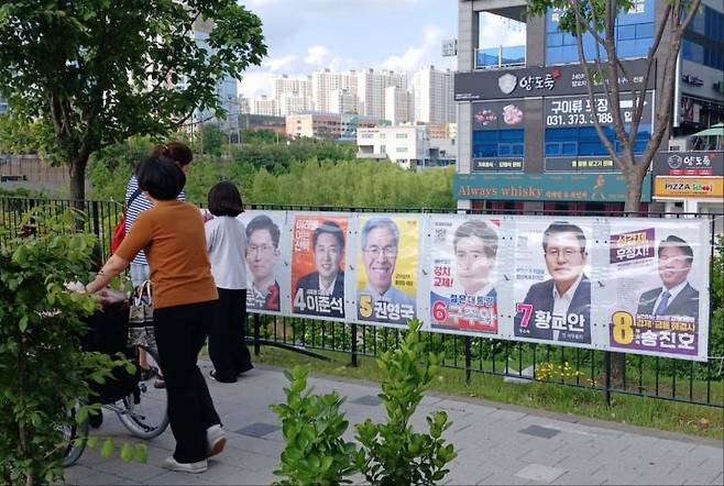 한 동탄 시민이 동탄호수공원에 위치한 송방천3교에 부착된 선거 벽보를 아이와 함께 들여다보고 있다.(사진=이동우 기자)