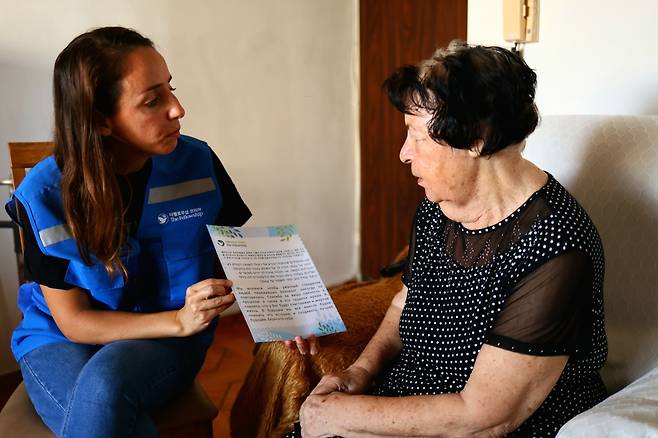 더펠로우십 봉사자(왼쪽)가 지난해 9월 이스라엘 야슈켈론 지역에서 홀로코스트 생존자인 안나 이로바씨에게 홀로코스트 생존자 응원 메시지를 전달하고 있다. 더펠로우십코리아 제공