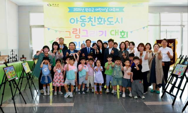 ▲26일 완주군청 1층 로비에서 열린 ‘2025 아동친화도시 그림그리기 대회’ 전시 개막식에서 유희태 완주군수와 입상자들이 함께 기념촬영을 하고 있다. ⓒ완주군 제공