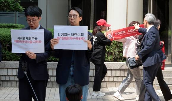 같은 장소 다른 마음 - 26일 서울 서초구 서울중앙지방법원 동관 앞에서 윤석열 전 대통령 재구속 촉구 의견서 제출 기자브리핑을 하는 참여연대, 군인권센터, 민주사회를 위한 변호사모임 회원들(왼쪽) 뒤로 윤 전 대통령의 지지자들이 손팻말을 펼치자 법원 관계자가 이를 제지하고 있다. 2025.5.26 연합뉴스