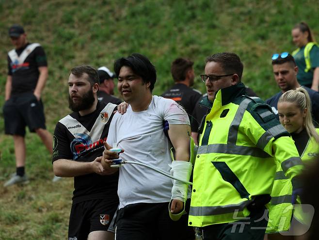 26일(현지시간) 영국 브록웍스의 쿠퍼스 힐에서 열린 '구르는 치즈 잡기' 대회에서 한 참가자가 부상을 당해 호송되고 있다. ⓒ 로이터=뉴스1