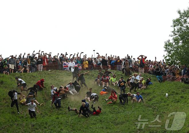 26일(현지시간) 영국 브록웍스의 쿠퍼스 힐에서 열린 '구르는 치즈 잡기' 대회에서 참가자들이 치즈를 쫒아 언덕을 내려가다 구르고 있다.  ⓒ 로이터=뉴스1