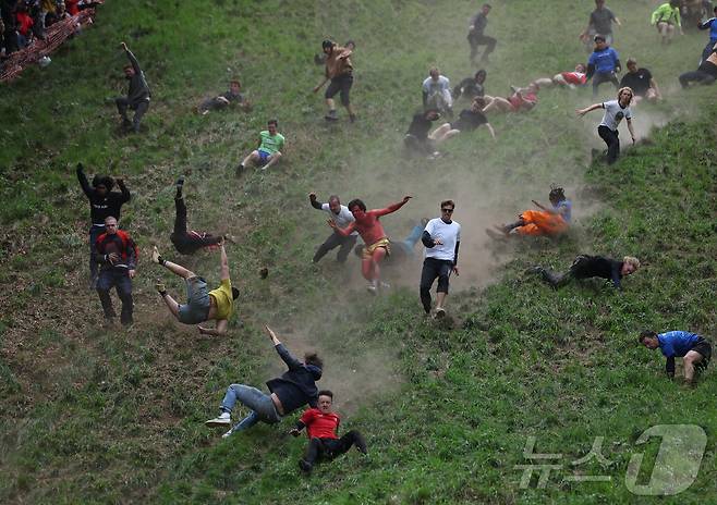 26일(현지시간) 영국 브록웍스의 쿠퍼스 힐에서 열린 '구르는 치즈 잡기' 대회에서 참가자들이 치즈를 쫒아 언덕을 내려가고 있다. ⓒ 로이터=뉴스1